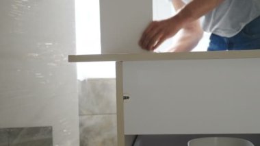 Tamirci yeni evinde mobilya parçaları topluyor. Mobilya montajı. Modern bir dairede çalışan marangoz ya da tesisatçı. Ev geliştirme ve yenileme konsepti. 4 k video