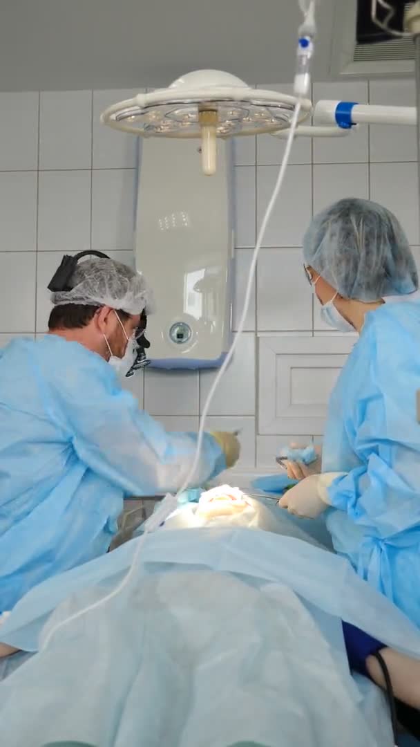 Cirurgiões dentários profissionais e assistente operando caso de cirurgia na sala de cirurgia. Médico e enfermeiro que trabalham em cuidados intensivos. Imagens verticais. Operação dentária realizada na clínica moderna. 4 k — Vídeo de Stock