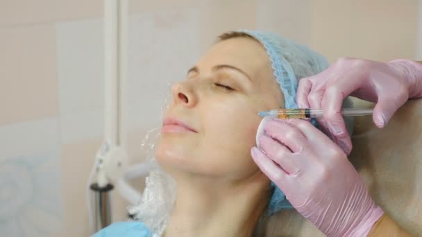 Procédure d'injection de beauté dans une clinique de beauté moderne. injection avec une seringue dans la joue féminine. Esthéticienne pratiquant la mésothérapie et le lifting du visage dans un salon de beauté. Vidéo 4 k — Video