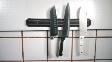 Restoranın mutfağındaki duvarlara mıknatıs yerleştirilmiş. Mutfak aletleri manyetik tutucuda asılı. Siyah eldivenli şef bir bıçak koyuyor. Yemek pişirmek için aletler. Keskin bıçak çeşitleri kullanıma hazır. 4 bin.