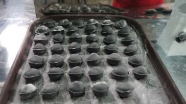 Modern gıda üretiminde hamur işi yapmak. Şefin elleri tepsiye siyah renkli hamur tatlısı koyuyor. Ev yapımı mı restoran yemeği mi? El yapımı etli börek. 4 k video