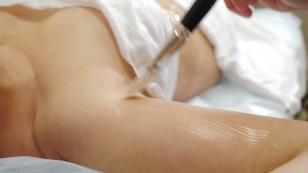 Klinika piękności. Kobieta dostaje profesjonalny zabieg zaciskania skóry ciała. Kosmetyk nakłada żel na żeńskie ramię pędzlem. Koncepcja renowacji skóry. kosmetyczka stosuje żel przewodzący. 4 tys. wideo — Wideo stockowe