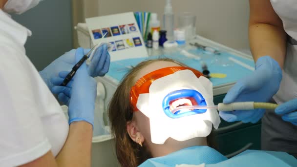 Procedimiento de blanqueamiento dental. Dentista hace blanqueamiento de dientes usando lámpara ultravioleta. Hermosa y perfecta sonrisa. Concepto odontológico moderno. Paciente en gafas protectoras mientras blanqueamiento led. Ultravioleta — Vídeo de stock