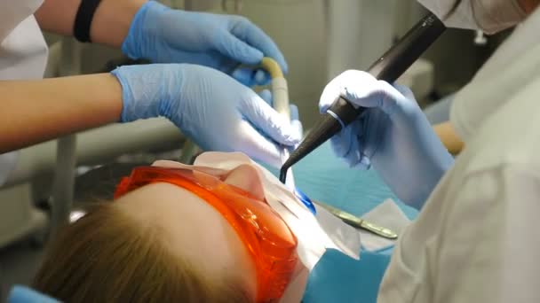 Soins dentaires en dentisterie moderne. Blanchiment oral professionnel en clinique utilisant une lampe ultraviolette. Sourire parfait avec des dents blanches. Procédure de blanchiment des dents. Patient dans des lunettes de protection tandis que LED — Video