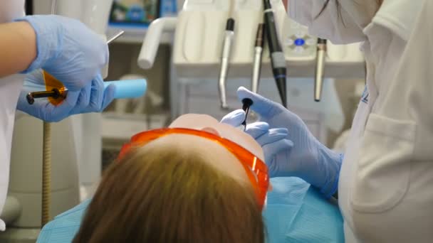 Equipe de médicos preparando paciente fêmea para dentes batendo gengivas isolantes. Sorriso perfeito com dentes brancos. Procedimento de clareamento dos dentes. 4 k vídeo — Vídeo de Stock