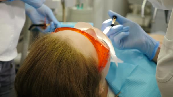 Egy csapat orvos felkészíti a női pácienst a fogazatra izoláló ínyre. Modern fogászati klinika. Tökéletes mosoly fehér fogakkal. Fogfehérítő eljárás. 4 k videó — Stock videók