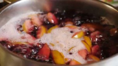 Cooking compot. beverage made of variety fresh berries. Boiling water with berries in saucepan mixing and stirring woth ladle. Rich, red, refreshing drink with bubbles, foam. Making delicious homemade