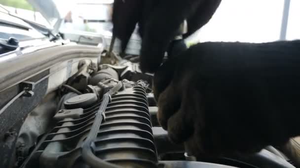 Mecánica de automóviles en guantes reparando coches en la estación de servicio. Mecánico del coche usando llave inglesa para reparar el motor, servicio del coche. Nuevas piezas de repuesto. centro de servicio de reparación. Primer plano de tiro. 4 k vídeo — Vídeo de stock