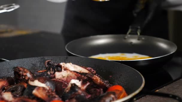 Restaurant de fruits de mer. Pieuvre bouillante dans une poêle à fruits avec vapeur montant sur fond noir. Chef en gants noirs ajoutant des épices en arrière-plan. cuisine dans la cuisine du restaurant. Délicieux gros poulpe — Video