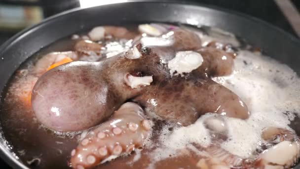 Oktopus kochen, indem man ihn in der Pfanne kocht, wobei Dampf auf schwarzem Hintergrund aufsteigt. Meeresfrüchte kochen in der Restaurantküche. Köstlicher großer Krake, der in der Pfanne kocht. Wasser kocht. Krake macht sich bereit — Stockvideo