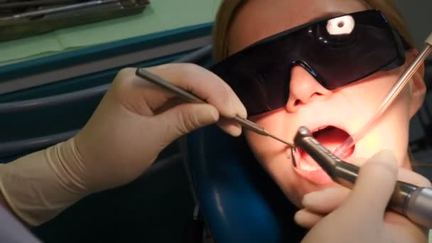 Dentista examinando dentes com instrumentos médicos. Retrato de uma jovem de óculos a verificar os dentes. Paciente de boca aberta. Tratamento dentário. Estomatologia médica moderna. 4 k vídeo — Vídeo de Stock