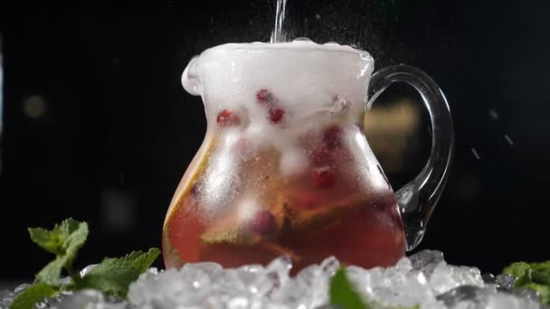 Belüftetes kaltes Wasser, das in transparente Gläser mit geschnittenen Limetten, Beeren und Eiswürfeln gegossen wird. Zeitlupe. Barkeeper macht sommerfrische Cocktails. Nachtleben und Nachtclub. Volle Konzentration — Stockvideo