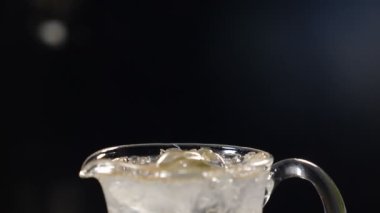 Dilimlenmiş kireç, nane yaprağı ve buzla dolu cam kavanoza soda dökülüyor. Yaz meyvesi ve böğürtlen. Masada buz küpleriyle siyah arka planda taze bir kokteyl. Yavaş çekim