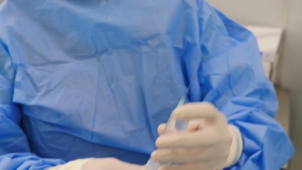 Koruyucu iş kıyafetleri hemşiresi şırınga basıyor ve ilaç sıkıyor. Modern klinikte damar cerrahisi hazırlığı. Cerrahi önlüklü ve eldivenli profesyonel doktorlar bir şeyler hazırlıyorlar. — Stok video