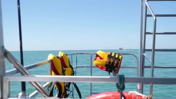 Bright orange life jackets on boat in open sea. POV from bridge or bow of ship. Fast sailing speed boat gliding over sea or ocean. Move forward on sea in great white sailing yacht. Fine ripples along — Stock Video