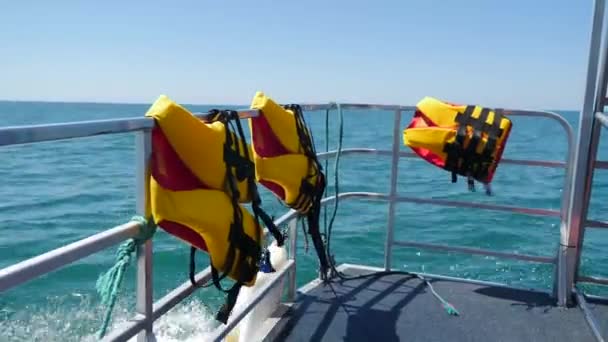 Яркие оранжевые спасательные жилеты на лодке в открытом море. POV с моста или носа корабля. Быстрый парусный катер скользит над морем или океаном. Двигайтесь вперед на большой белой парусной яхте. Мелкие колебания вдоль — стоковое видео