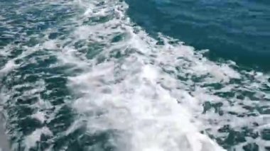 Yelkenli geminin arkasında su köpüğü izi var. Denizde hızla ilerleyen motorlu tekne, arkadaki yat yolu manzarası. Motorun arkasında köpük izi olan motorlu sürat teknesinin arka görüntüsü. 4 k video
