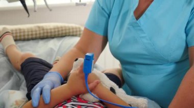 Ameliyathanede cerrahi müdahale. Modern diş kliniğinde çocuk anestezi altında tedavi görüyor. Hemşire, nabız oksimetresine kalp atışlarını ölçüyor. Nabzı ölç