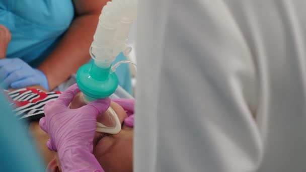 麻酔中の没入型の子供。一般的なナルコシスの下で現代病院で動作します。手術室の酸素マスクで指呼吸の薬パルス酸素濃度計を持つ未確認の少年。4 kビデオ — ストック動画