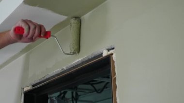 Ev geliştirme ve yenileme konsepti. Erkek boyacı, duvarları silindirle boyuyor. İsimsiz ressam iş başında. Profesyonel resim servisi. Ev onarımı ve bitirme işleri. İç mekan