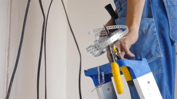 Installatie van elektrische bedrading op het plafond en de muur van het appartement. Elektrische kabel systeem instelling. Elektricien repareert draden. Huisverbetering en renovatie. Elektricien zet elektrische kabel in — Stockvideo