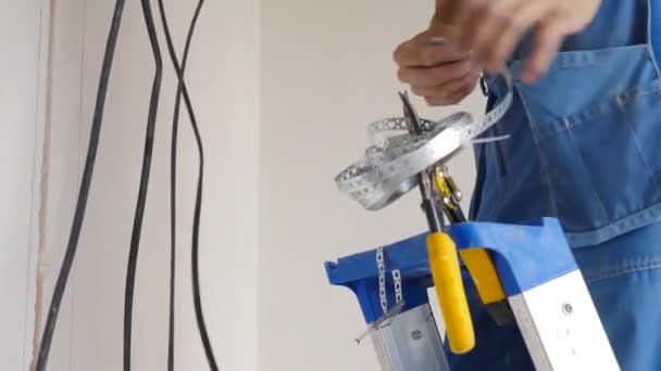 Installazione di cavi elettrici sul soffitto e sulla parete dell'appartamento. Impostazione del sistema di cavi elettrici. Elettricista che ripara fili. Miglioramento e ristrutturazione della casa. L'elettricista inserisce il cavo elettrico — Video Stock