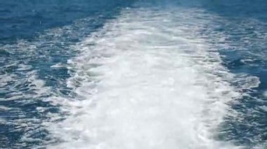 Yelkenli geminin arkasında su köpüğü izi var. Denizde hızla ilerleyen motorlu tekne, arkadaki yat yolu manzarası. Motorun arkasında köpük izi olan motorlu sürat teknesinin arka görüntüsü. 4 k video