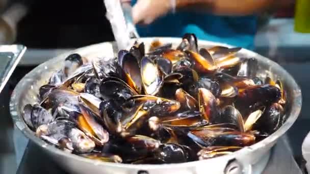 Comida de rua mexilhões e conchas. Cozinhar e misturar frutos do mar com molho picante panela grande. Venda de comida de rua no mercado local ou festival. Cozinha mediterrânea. Fritar em assadeira grande, fervendo — Vídeo de Stock