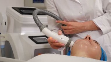 Donanım kozmetolojisi olan modern güzellik kliniği. Orta yaşlı bir kadın cilt bakımı yaptırıyor. Deri gençleştirme. Olgun bir müşteri yüz gerdirme tedavisi görüyor. 4 k video