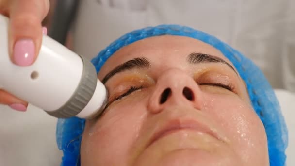 Clinique de beauté moderne avec cosmétologie matérielle. Femme d'âge moyen obtenant rf lifting soin du visage procédure. rajeunissement de la peau. Client mature recevant un traitement de lifting du visage. Vidéo 4 k — Video