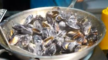 Sokak yiyeceği midye ve deniz kabuğu. Baharatlı sosla büyük tavada deniz ürünleri pişirip karıştırmak. Yerel pazarda ya da festivalde sokak yemekleri satılıyor. Akdeniz mutfağı. Kızgın bir ateşte yakılacaklardır.