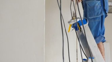 Dairenin tavanına elektrik kabloları döşenmiş. Elektrik kablosu ayarı. Elektrikçi kabloları tamir ediyor. Ev tadilatı. Elektrikçi prefabrik binaya elektrik kablosu yerleştiriyor. 4 bin.