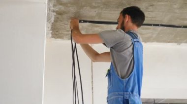 Dairenin tavanına elektrik kabloları döşenmiş. Elektrik kablosu ayarı. Elektrikçi kabloları tamir ediyor. Ev tadilatı. Elektrikçi prefabrik binaya elektrik kablosu yerleştiriyor. 4 bin.
