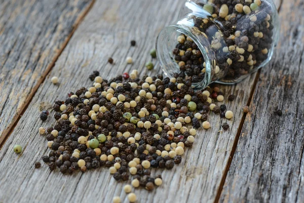 Peppercorn spilling out of a glass jar — Stock Photo, Image