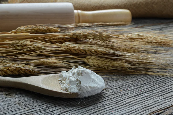 Pino de rolamento com trigo e colher com farinha e pão — Fotografia de Stock