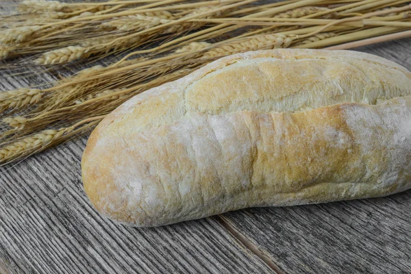 Pão e trigo no fundo de madeira rústica — Fotografia de Stock