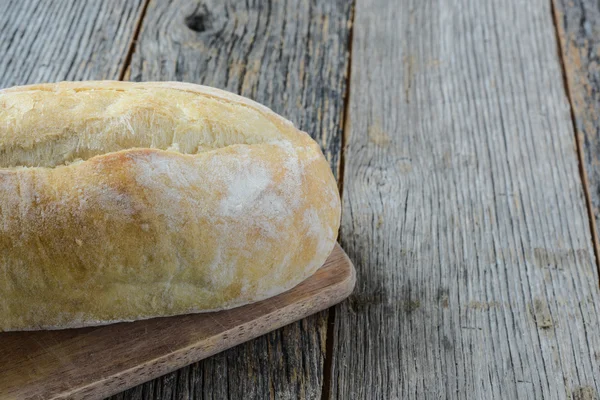 Pan en un tablero de pan con fondo de madera rústica —  Fotos de Stock