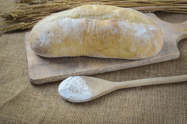 Brot auf Brotbrett mit Weizen und Mehl gefülltem Löffel auf Klette — Stockfoto