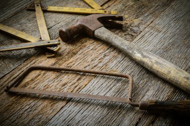 Hammer, Saw and Measuring Tape on Rustic Wood Background