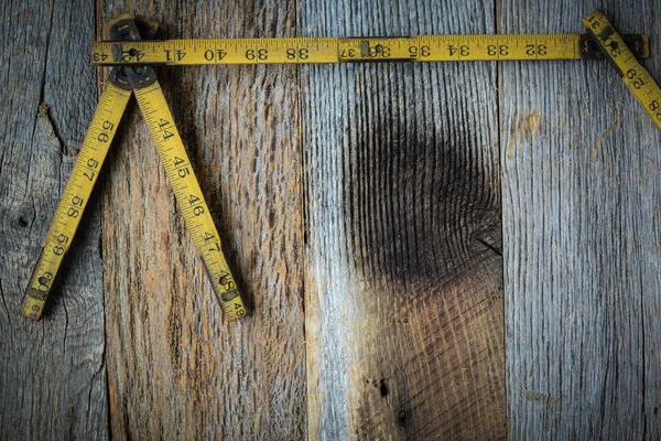 Cinta métrica antigua para la construcción sobre fondo de madera rústica — Foto de Stock