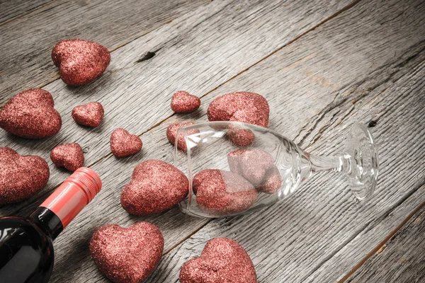 Bicchiere di vino e bottiglia di vino con cuori rossi a San Valentino — Foto Stock