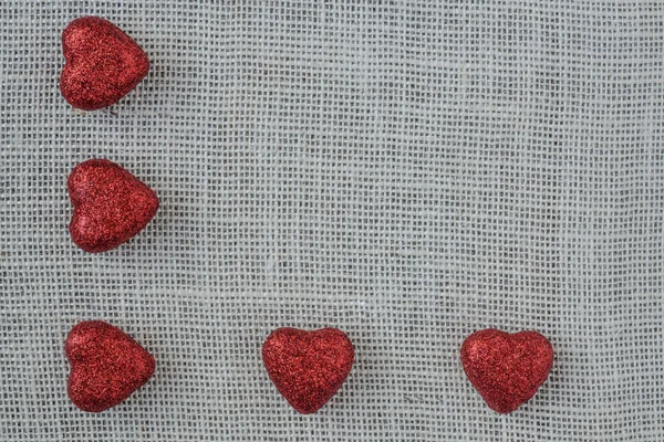 Corazones rojos sobre fondo de arpillera —  Fotos de Stock