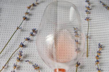 Kuru lavanta çiçekleri ve beyaz waffle pamuğunun üzerinde bir kadehte bir yudum gül şarabı. Provencal gül şarabı konsepti.