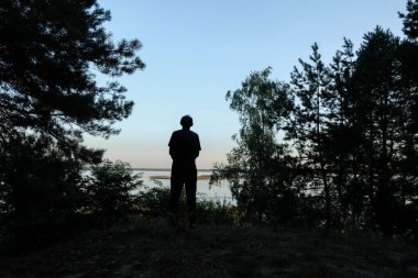 Günbatımı arka planında yansıyan adam. Siluet. Göl. Boşluğu kopyala.