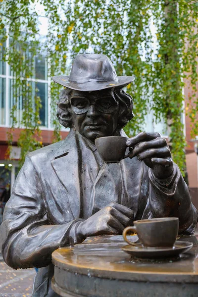 stock image September 30, 2020. Lutsk, Volyn, Ukraine. Bronze sculpture of a man with a cup of coffee on a rainy day. Poet bard sixties Kostya Shishko. Vertical image.