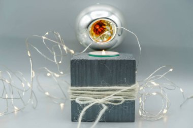 Beyaz ve gri Noel dekoru. Yünlü iplikli gri ahşap şamdan. Gümüş Noel balosu. Telli lambalar. Boşluğu kopyala.