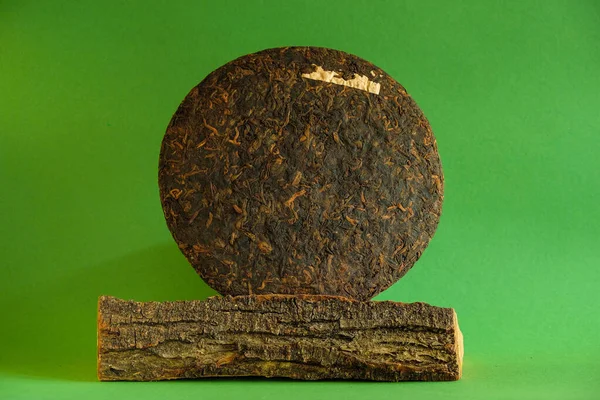 China Yunnan Puer tea cake. Tree bark. Green background. Minimalism. Copy space. Mockup.