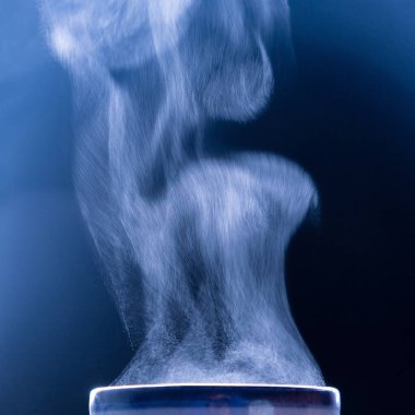 Mavi üzerindeki buhar dokusu. Sıvı buharlaşması. Karanlık fotoğraf. Kare görüntü. Boşluğu kopyala.