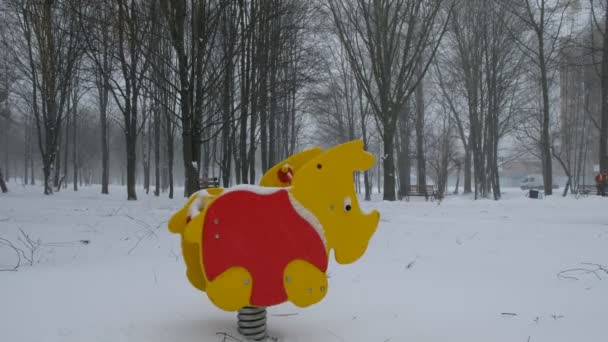 Bunte Einsam Schaukelnde Nashörner Auf Einem Kinderspielplatz Bei Schneefall Leerer — Stockvideo