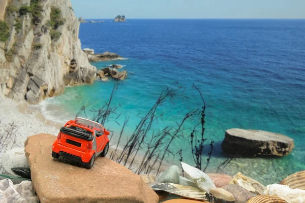 Children's red toy car on the stone. Sea background. Rent a car concept. Travel and vacation concept. Copy space.